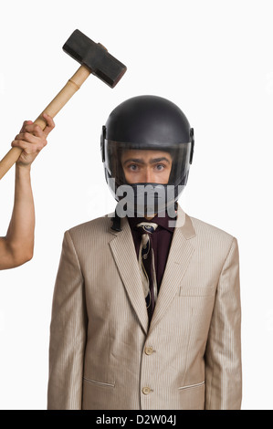 persons-hand-hitting-a-hammer-on-a-businessman-wearing-a-helmet-d2w04j.jpg
