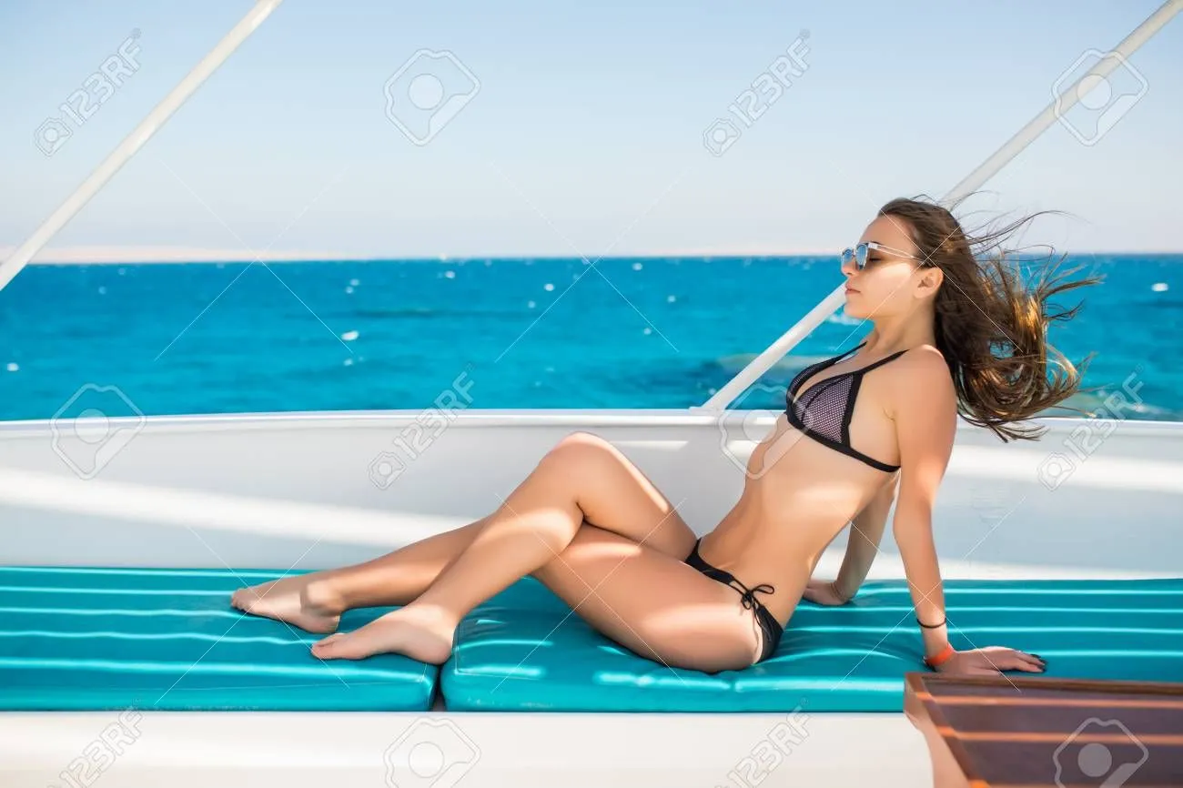 95812754-young-woman-in-a-black-swimsuit-sunning-on-a-yacht-in-the-open-sea-on-a-sunny-day.webp