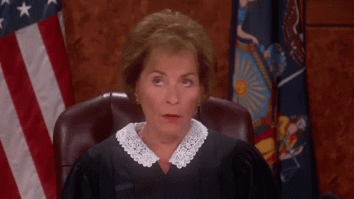 a-woman-in-a-judge-s-robe-sitting-in-front-of-an-american-flag-l6vud8bbtml1nqim.gif