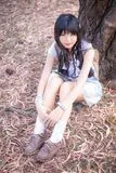 cute-asian-thai-girl-sitting-her-knees-up-under-tr-tree-tablet-laps-51696807.webp