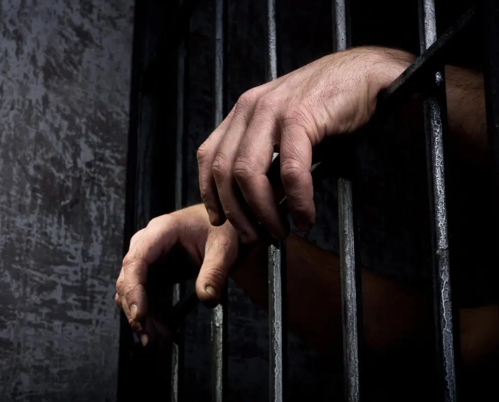 hands-behind-prison-bars.webp