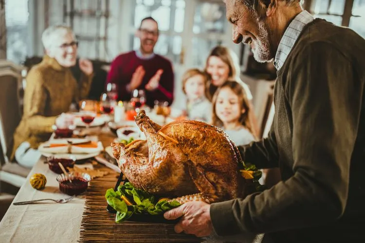 man-carrying-turkey-dinner-table.webp