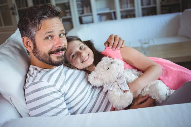 smiling-father-daughter-sitting-sofa-teddy-bear-portrait-78713919.jpg