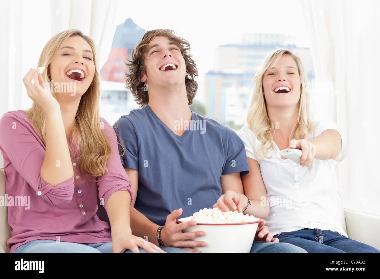 three-friends-eating-popcorn-while-laughing-at-the-show-CY9A32.webp