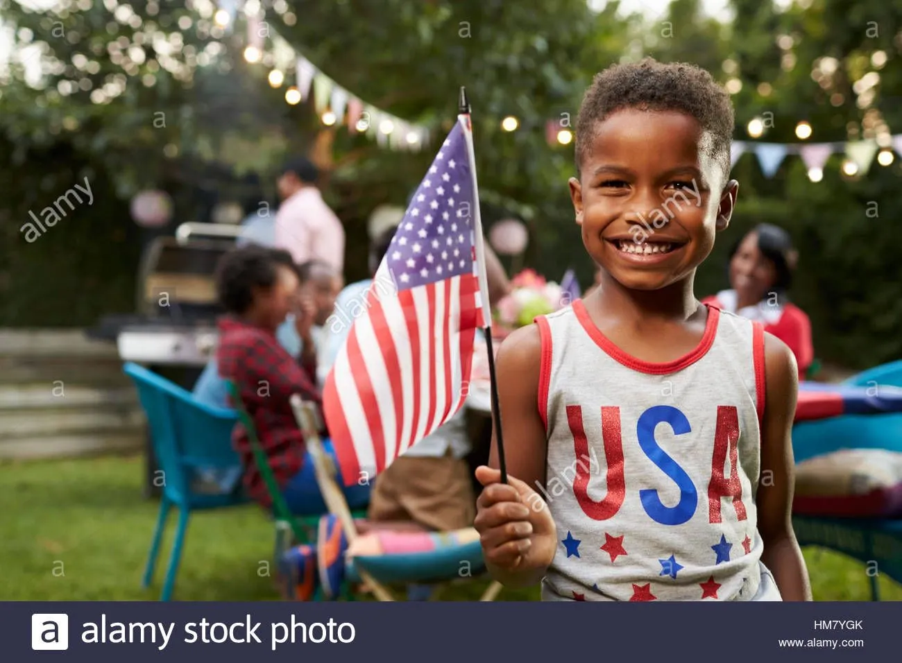 young-black-boy-holding-flag-at-4th-july-family-garden-party-HM7YGK.webp