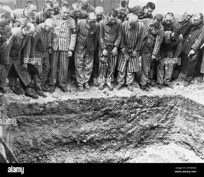 a-group-of-survivors-at-dachau-looking-into-an-open-mass-grave-dachau-was-the-first-nazi-conc...webp
