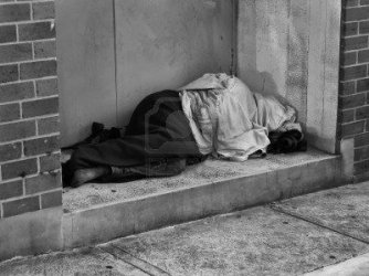 $8927645-a-homeless-man-bundled-up-under-a-jacket-asleep-in-a-city-doorway.jpg