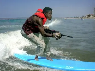 Funny-Man-With-Gun-On-Surfing-Board.webp