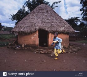 young-boy-running-past-mud-hut-with-bread-A1CP77.jpg