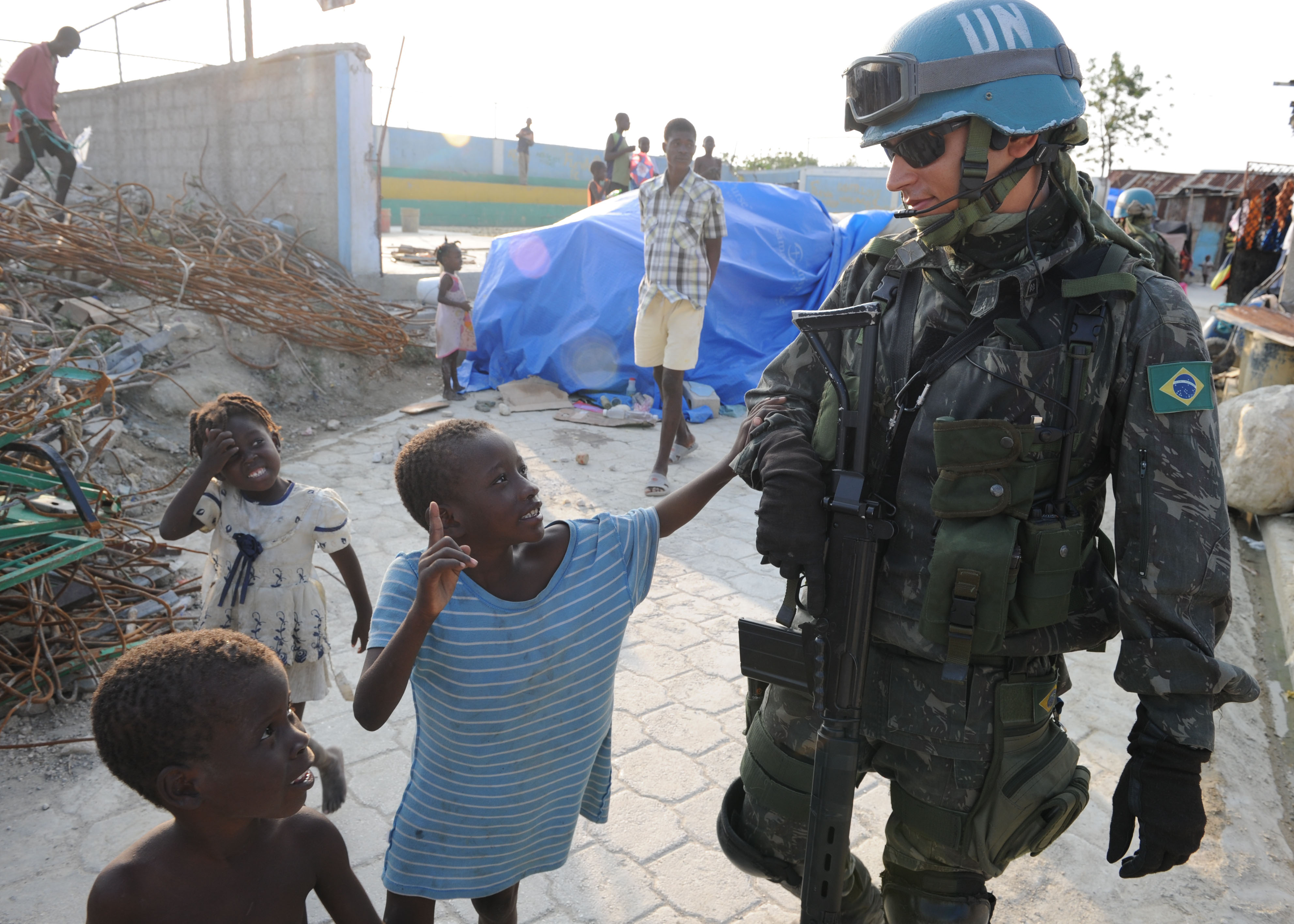 US_Navy_100316-N-9116F-001_A_Brazilian_U.N._peacekeeper_walks_with_Haitian_children_during_a_patrol_in_Cite_Soleil.jpg