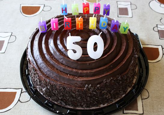 Round+chocolate+50th+birthday+cake+with+colorful+candles+spelling+out+Happy+Birthday.JPG